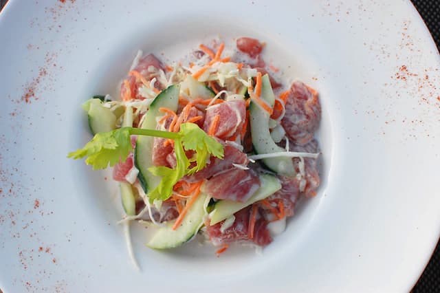 A bowl of kokoda - white pieces of fish in thick coconut cream with colourful vegetables