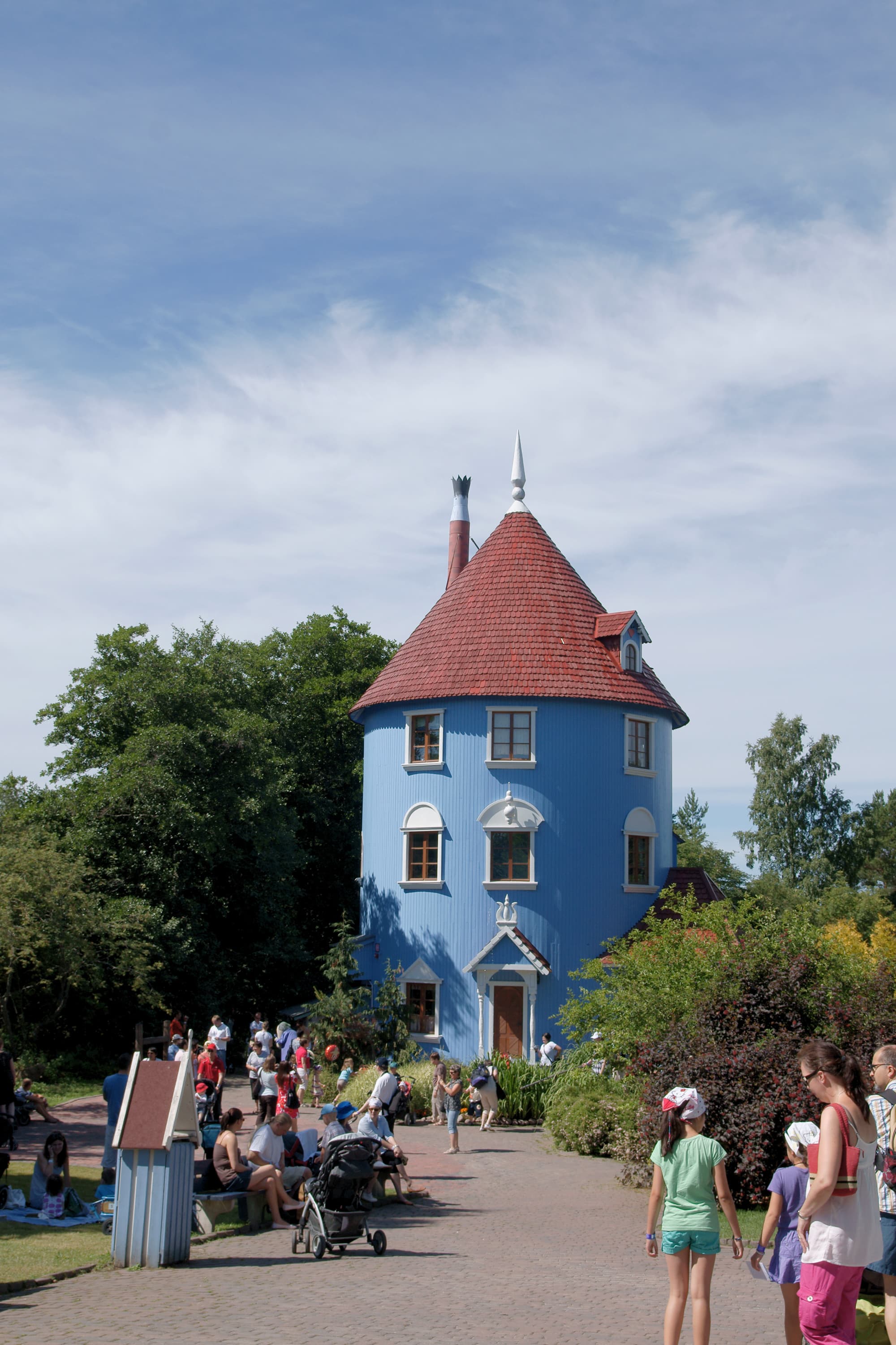 The tall, round blue Moomin house at Moomin World theme park in Naantali, with families visiting on a sunny day