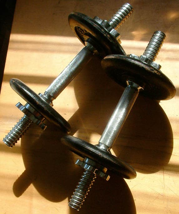 A weightlifter lifting a heavy barbell overhead at a competition