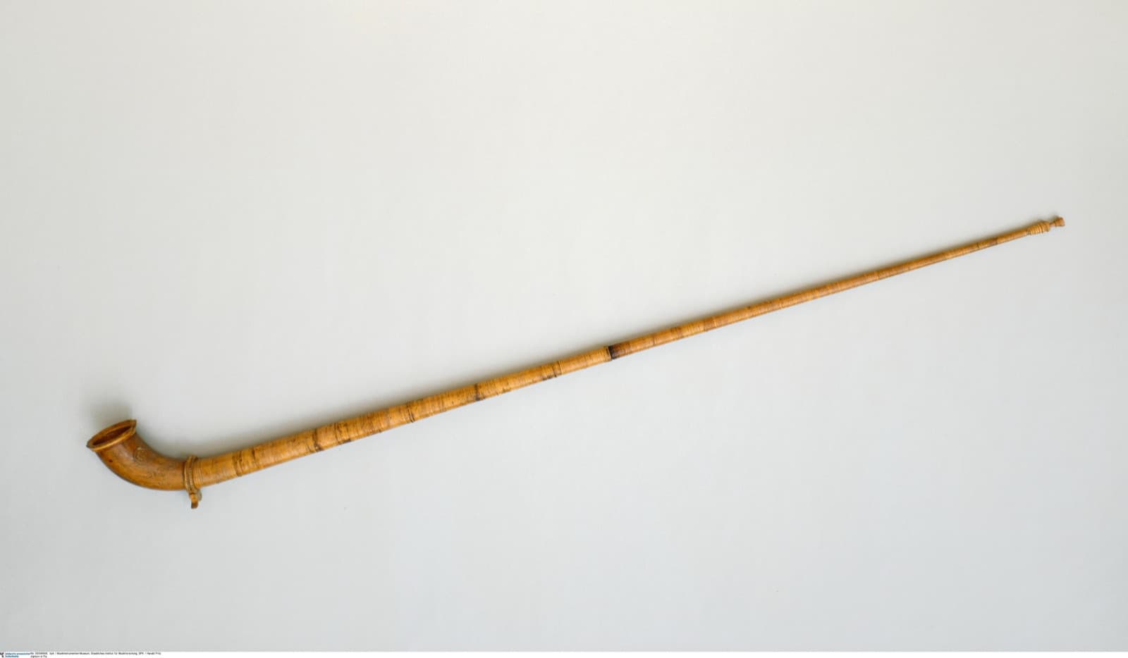 A musician playing a long wooden alphorn in the Swiss Alps