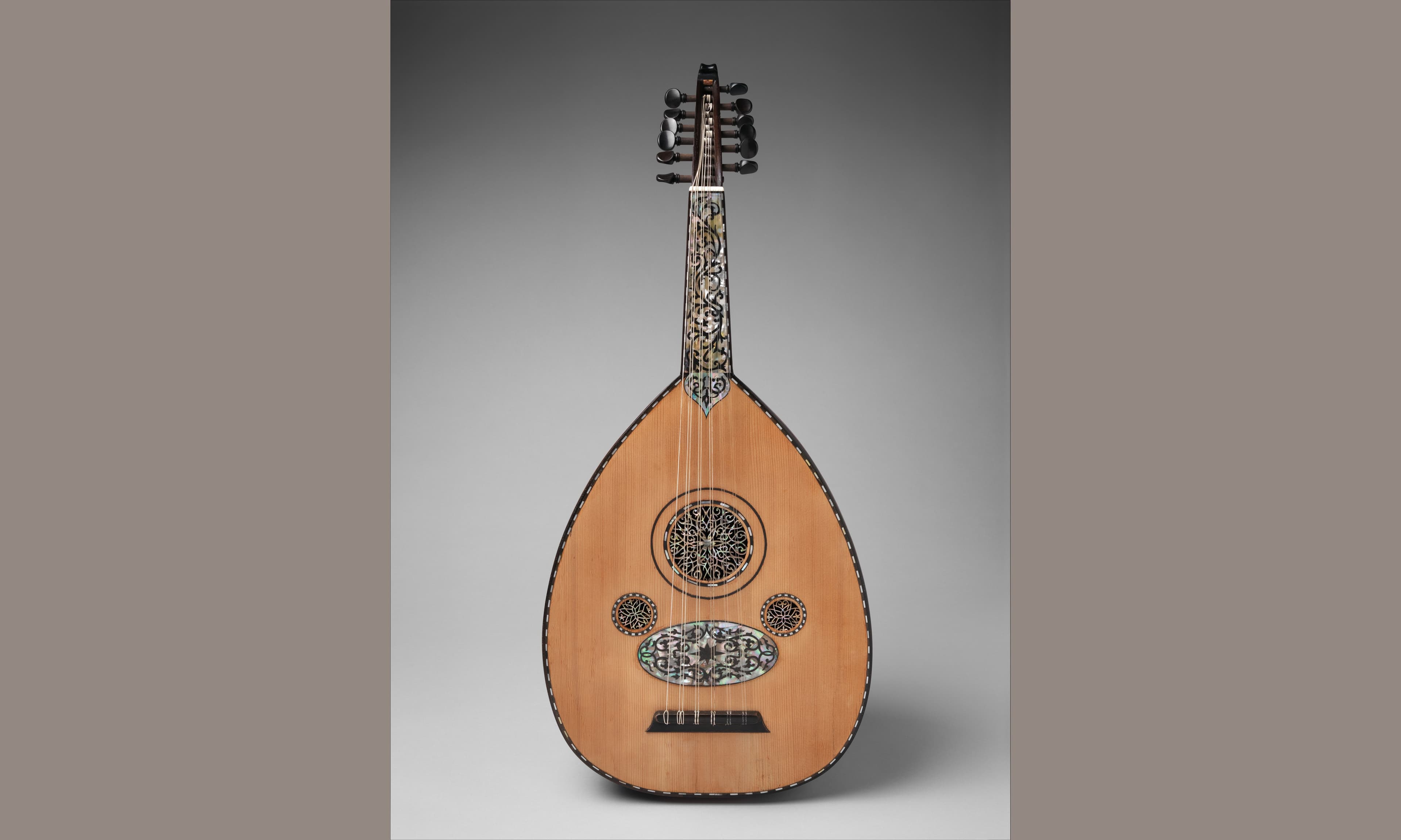 A craftsman holding a beautifully finished oud with its distinctive round wooden body and short neck
